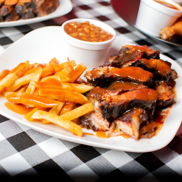 Terrell's Eat The Bone BBQ ribs with sauce, fries, and a side of baked beans on a checkered tablecloth.
